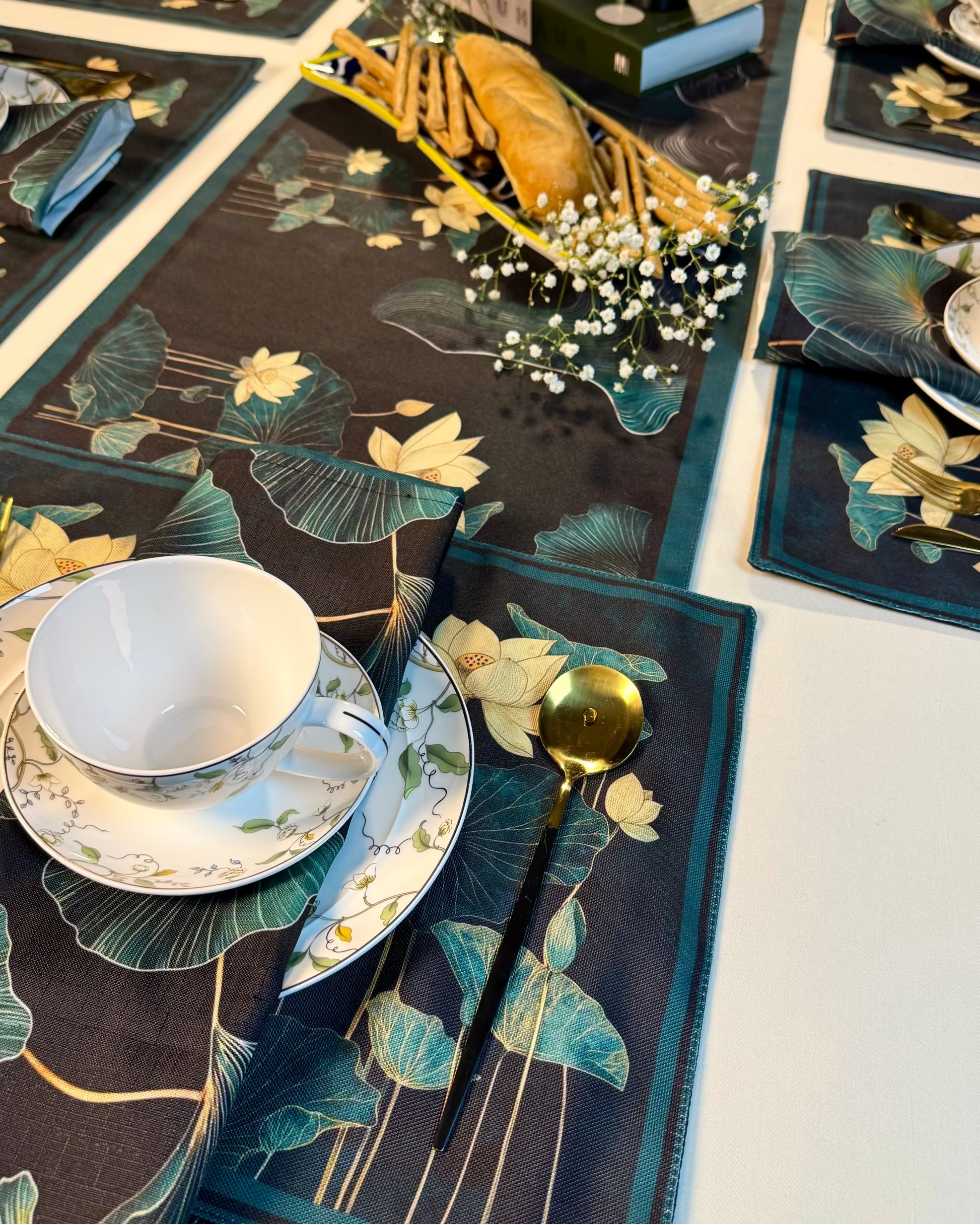 Table setting with floral placemats, plates, and cutlery on a white table.