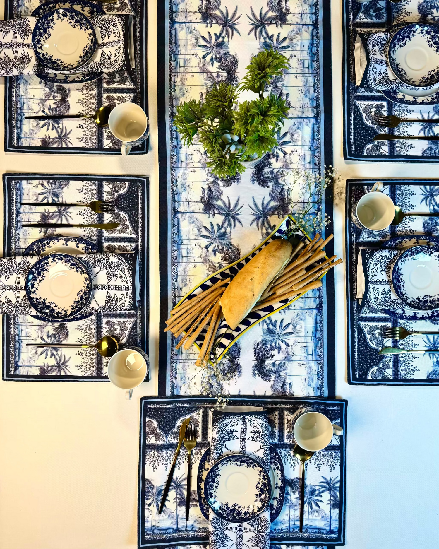 Decorative table setting with blue and white patterned tablecloth, plates, and centerpieces.