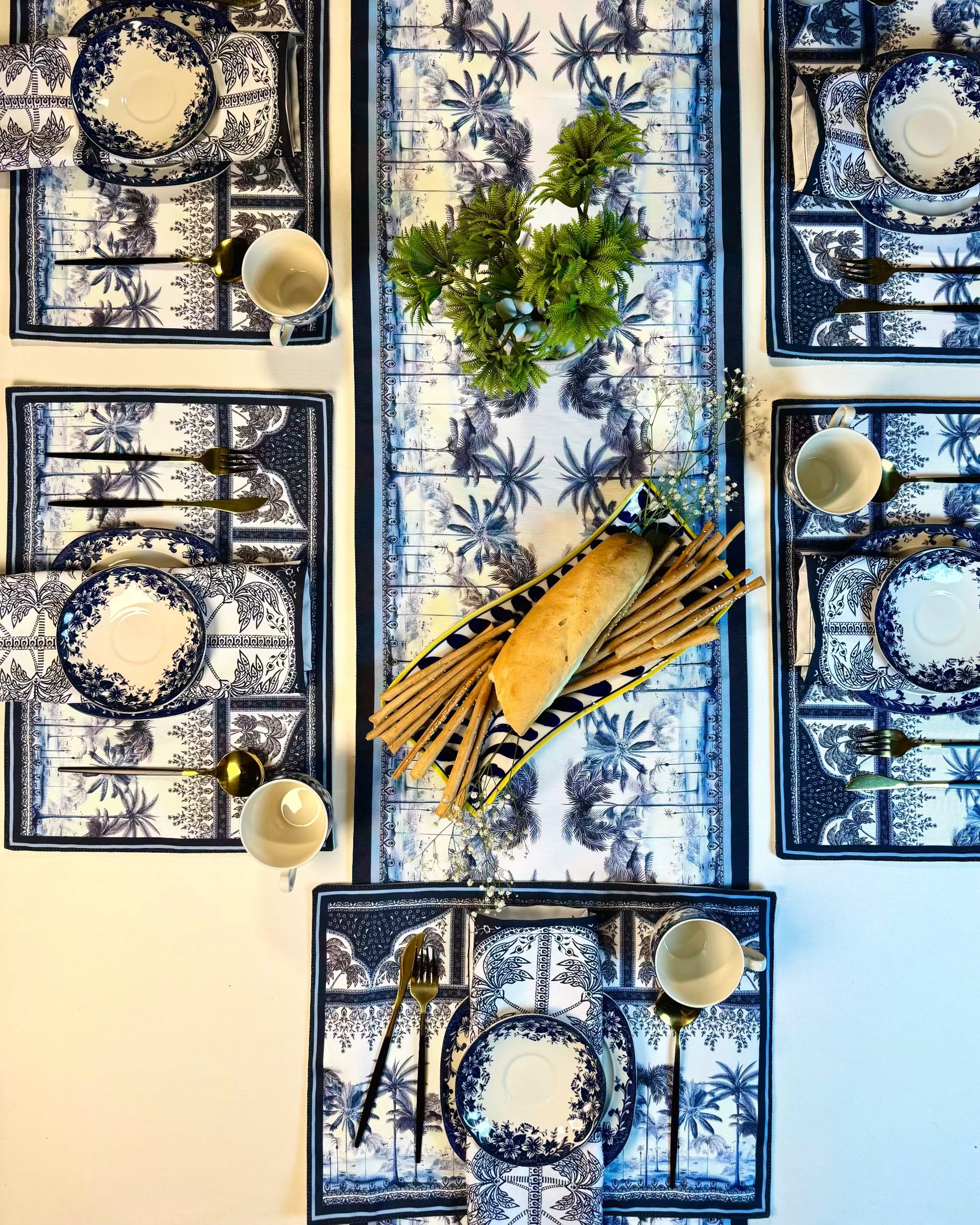 Decorative table setting with blue and white patterned tablecloth, plates, and centerpieces.