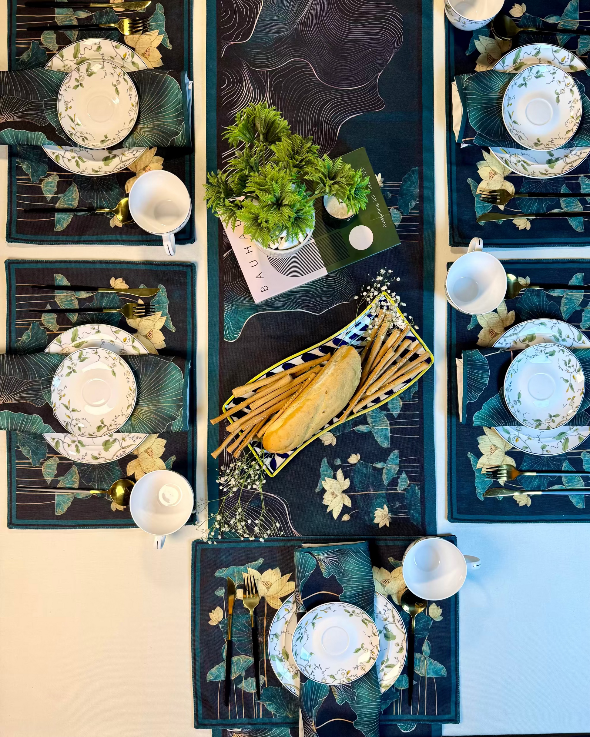 Decorative table setting with plates, cutlery, and a centerpiece on a dark surface.